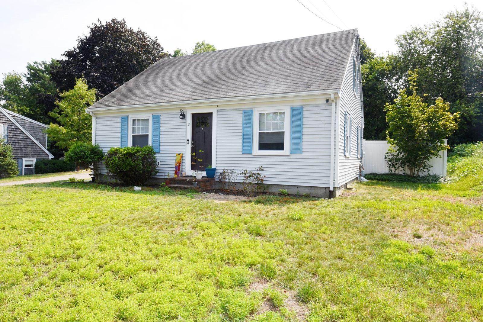18 Gould Road seen from the street: a white Cape with blue shutters and a lawn.